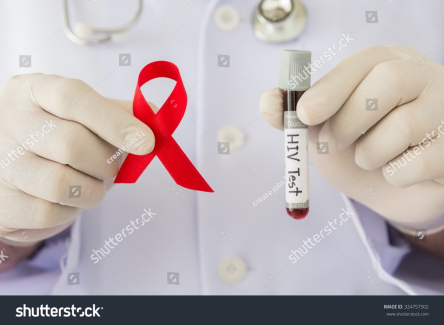 Kırmızı renkli HIV farkındalık kurdelesini ve HIV testini tutan hekim eli